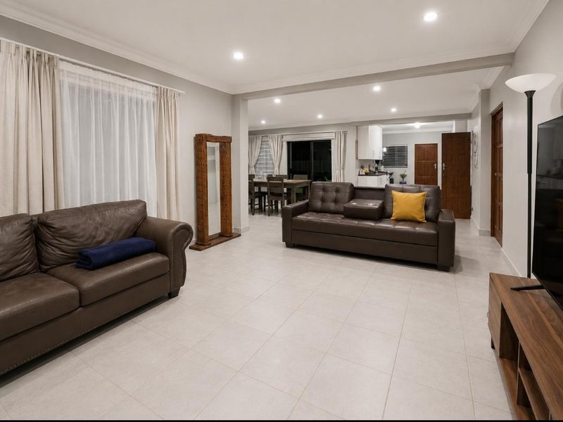 Spacious open-plan living and dining area featuring neutral tiled flooring, recessed lighting, and seamless flow into the adjacent kitchen space.