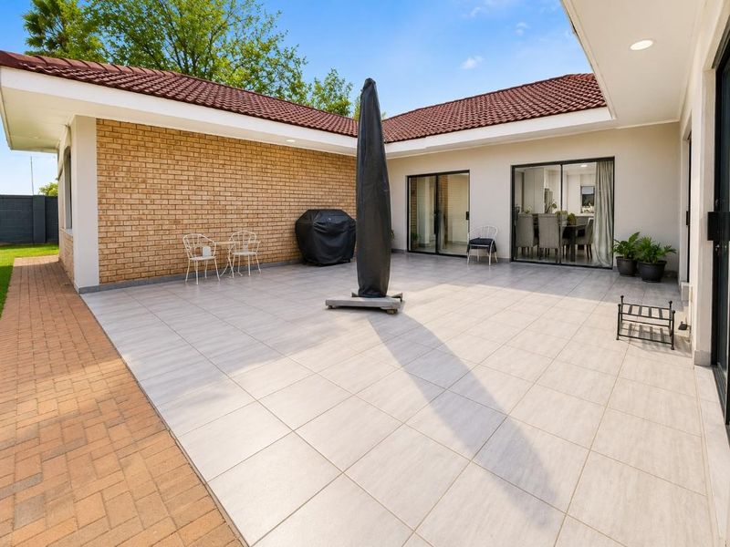 Spacious covered patio featuring tiled flooring, brick exterior wall, and sliding glass door access to the interior living area.