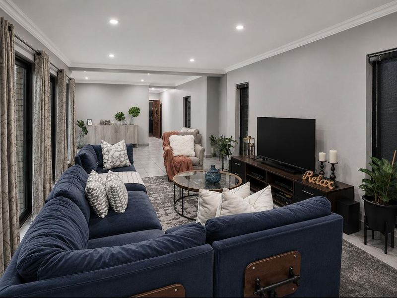 Spacious living room featuring neutral walls, recessed downlighting, tiled flooring, and large sliding glass doors providing ample natural light.
