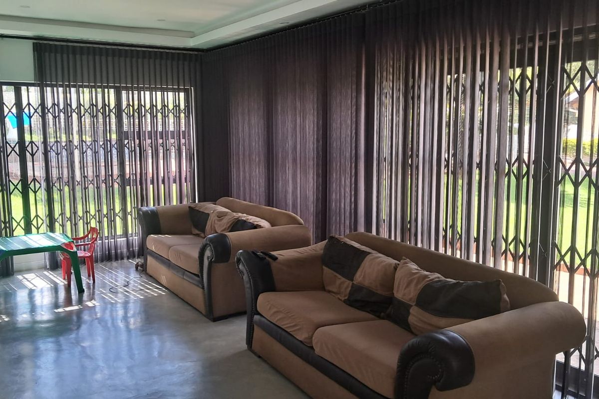 Spacious living area featuring polished concrete floors, recessed lighting, and large sliding glass doors with integrated security gates providing access to the garden.