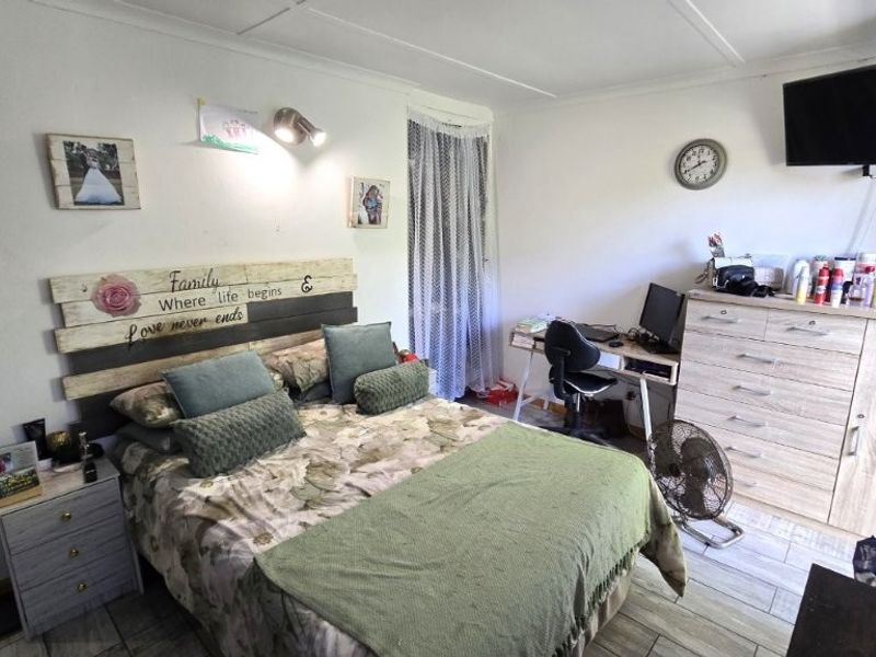 A functional bedroom featuring tiled flooring and a wall-mounted light fixture, offering a comfortable and practical living space.