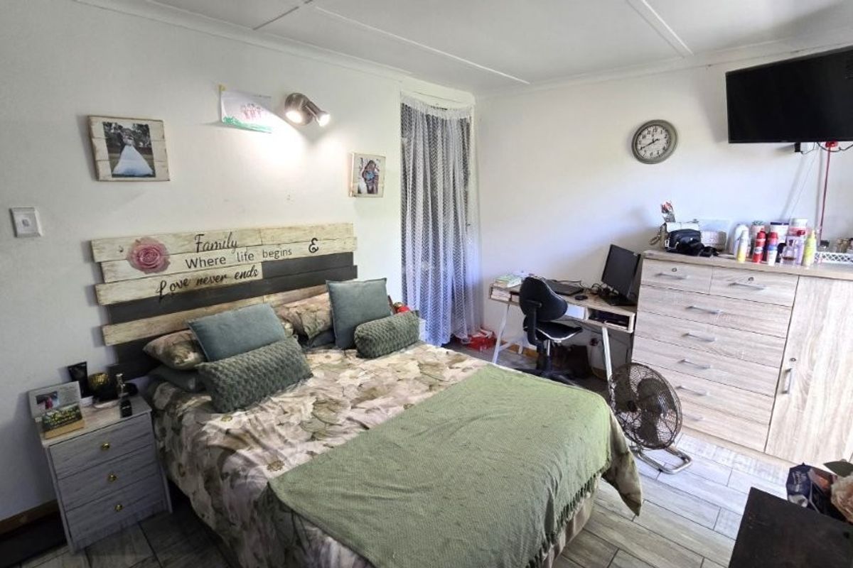 A functional bedroom featuring tiled flooring and a wall-mounted light fixture, offering a comfortable and practical living space.