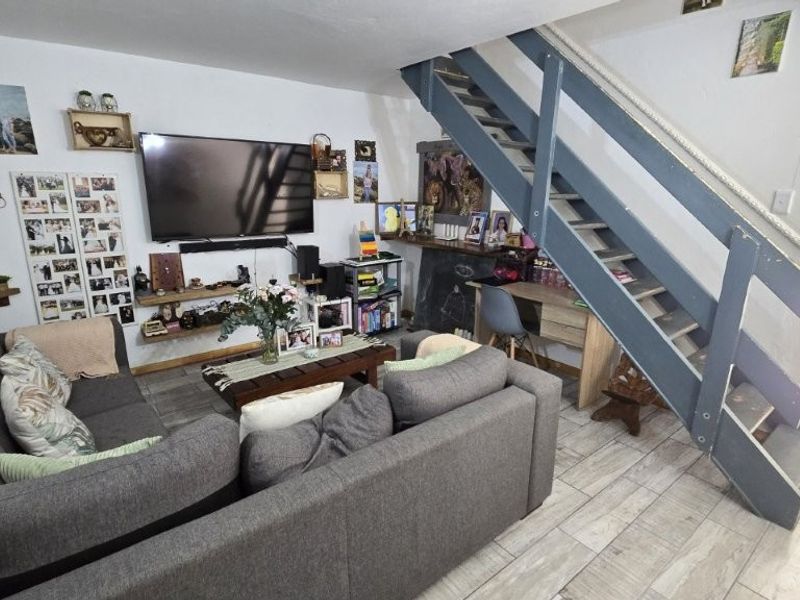 Open-plan living area featuring tiled flooring and a prominent staircase, providing a functional layout for daily living.