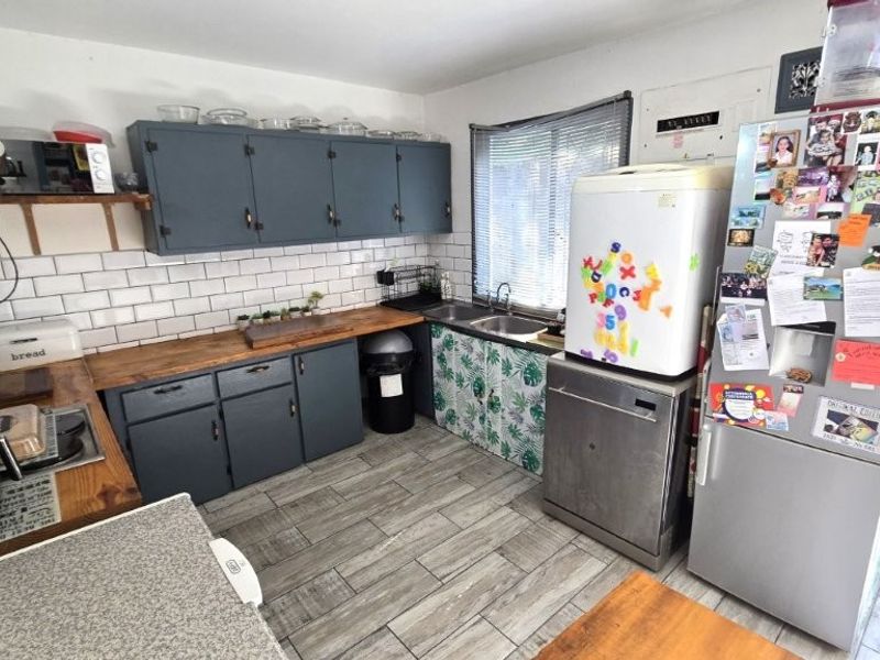 Functional kitchen featuring wooden countertops, subway tile backsplash, and ample cabinetry, offering a practical layout with potential for cosmetic updates.