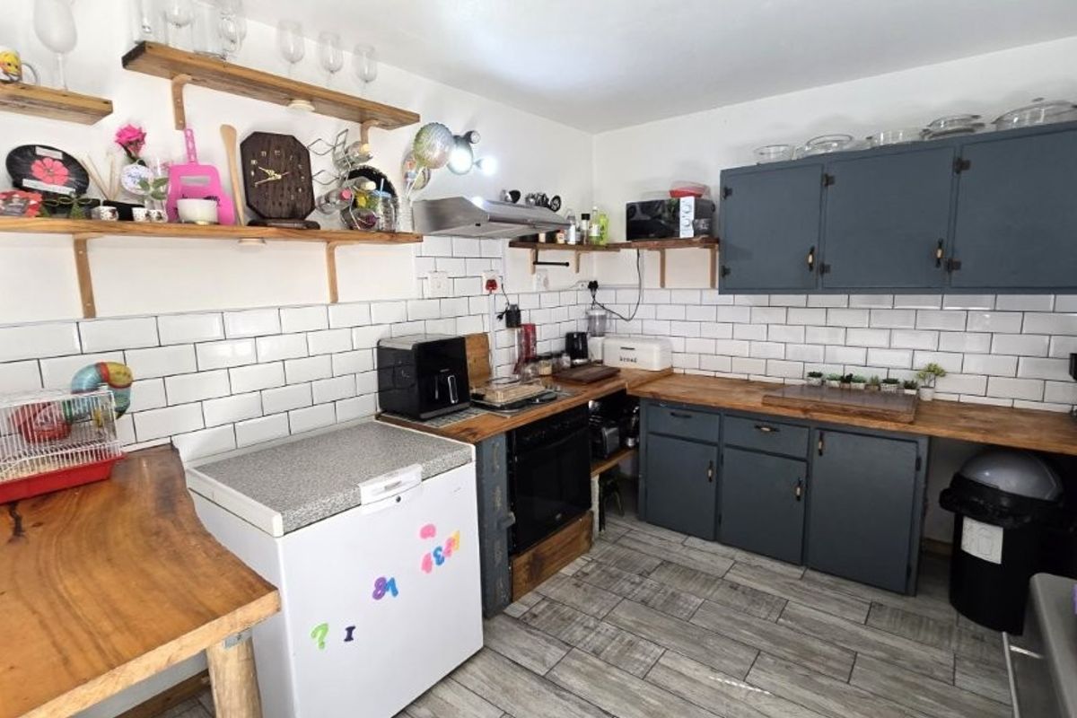 Kitchen featuring subway tile backsplash, wooden countertops, open shelving, and dark grey cabinetry with integrated oven and extractor fan.