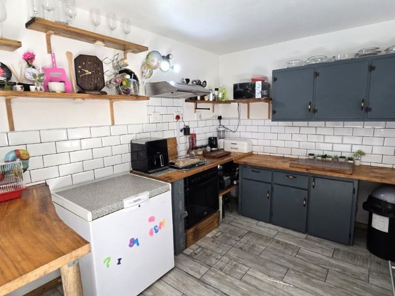 Kitchen featuring subway tile backsplash, wooden countertops, open shelving, and dark grey cabinetry with integrated oven and extractor fan.