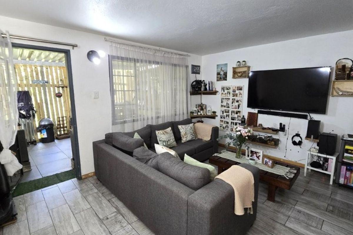 A comfortable living room featuring tiled flooring and direct access to an outdoor patio area through a sliding door.