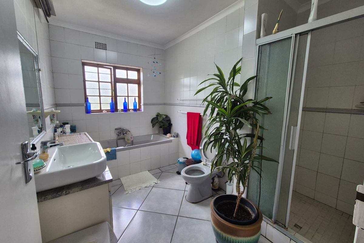 A functional bathroom featuring a built-in vanity, tiled bathtub, separate shower enclosure, and toilet, finished with neutral ceramic wall and floor tiles.