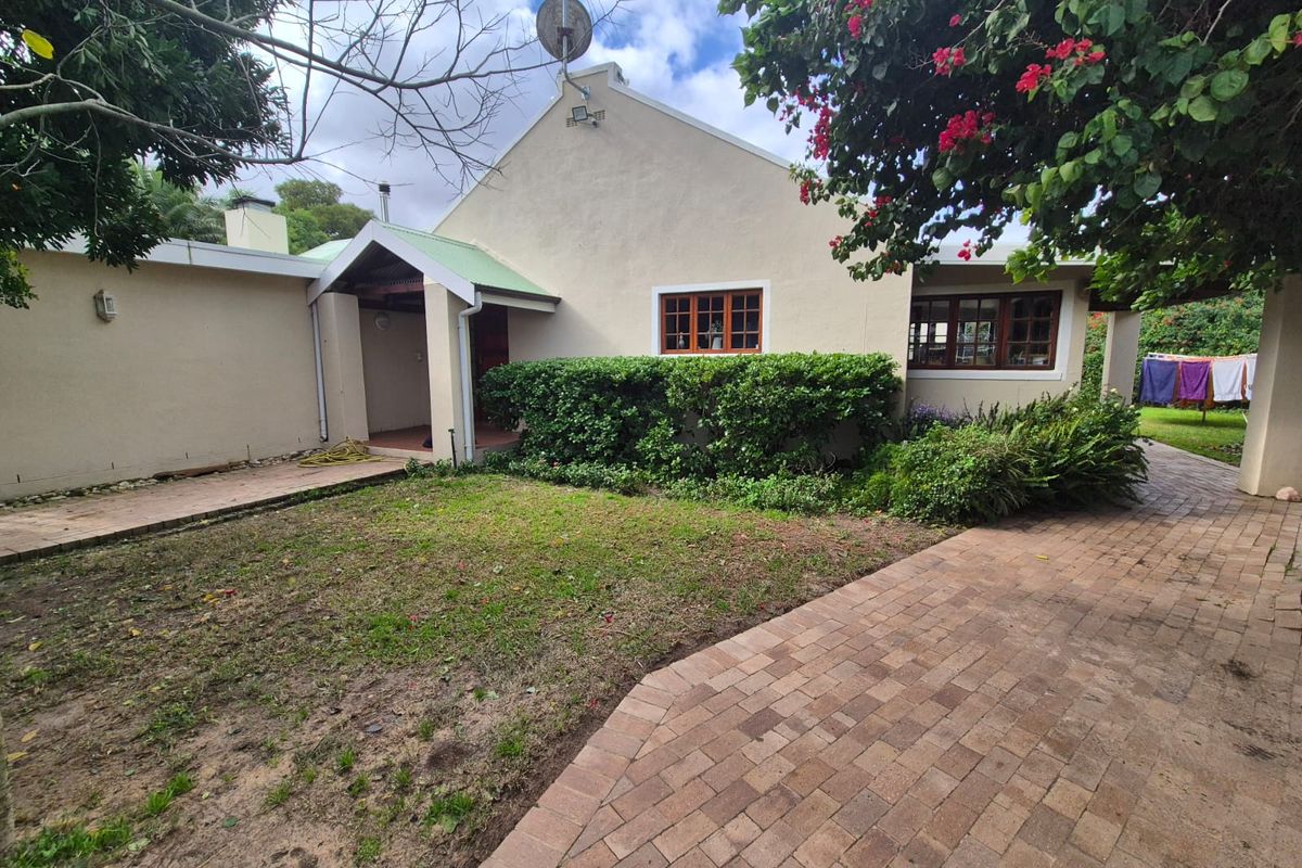 Rear view of the farm property featuring a brick paved path, covered entrance, and established garden surroundings.