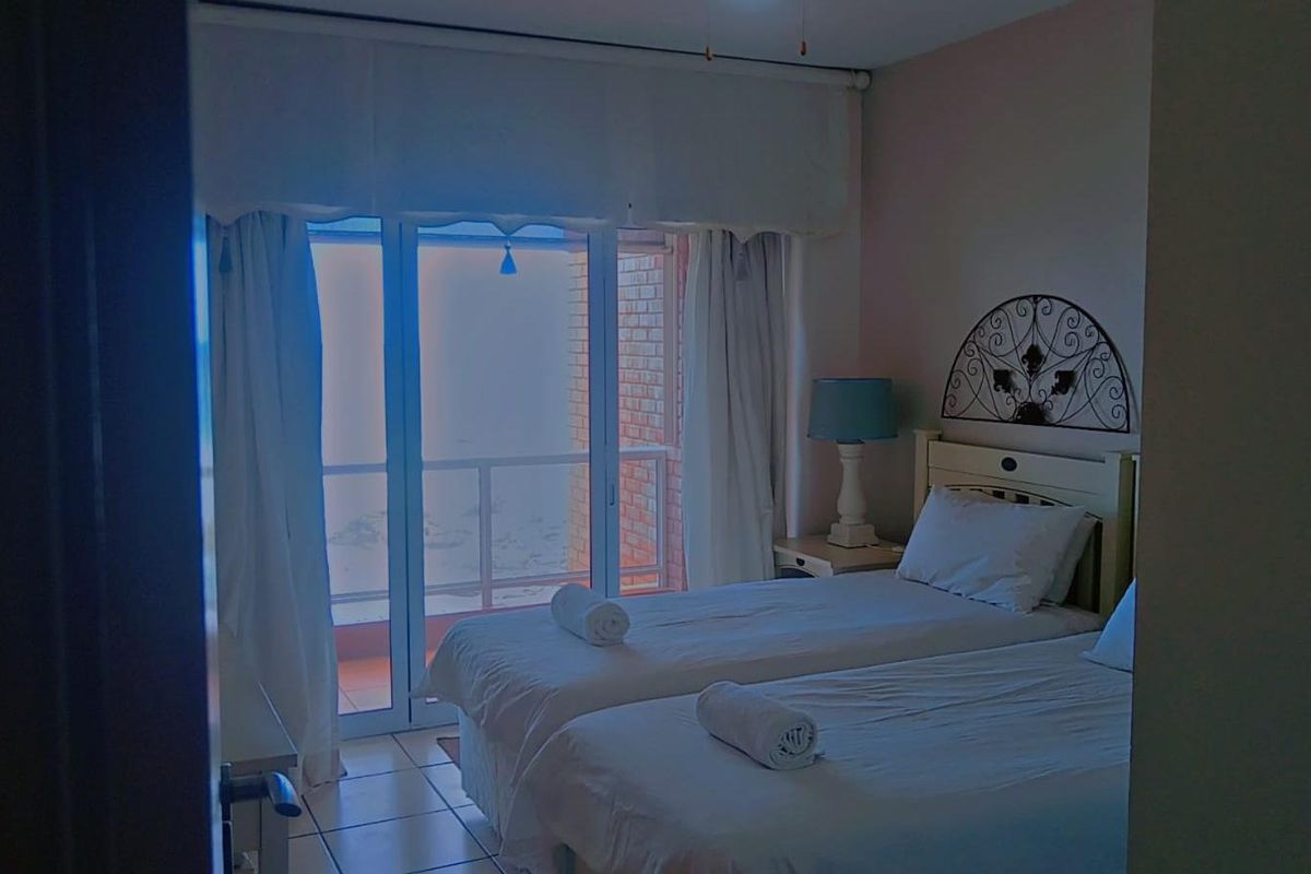 A bedroom featuring tiled flooring and sliding glass doors that open onto a private balcony with exterior views.