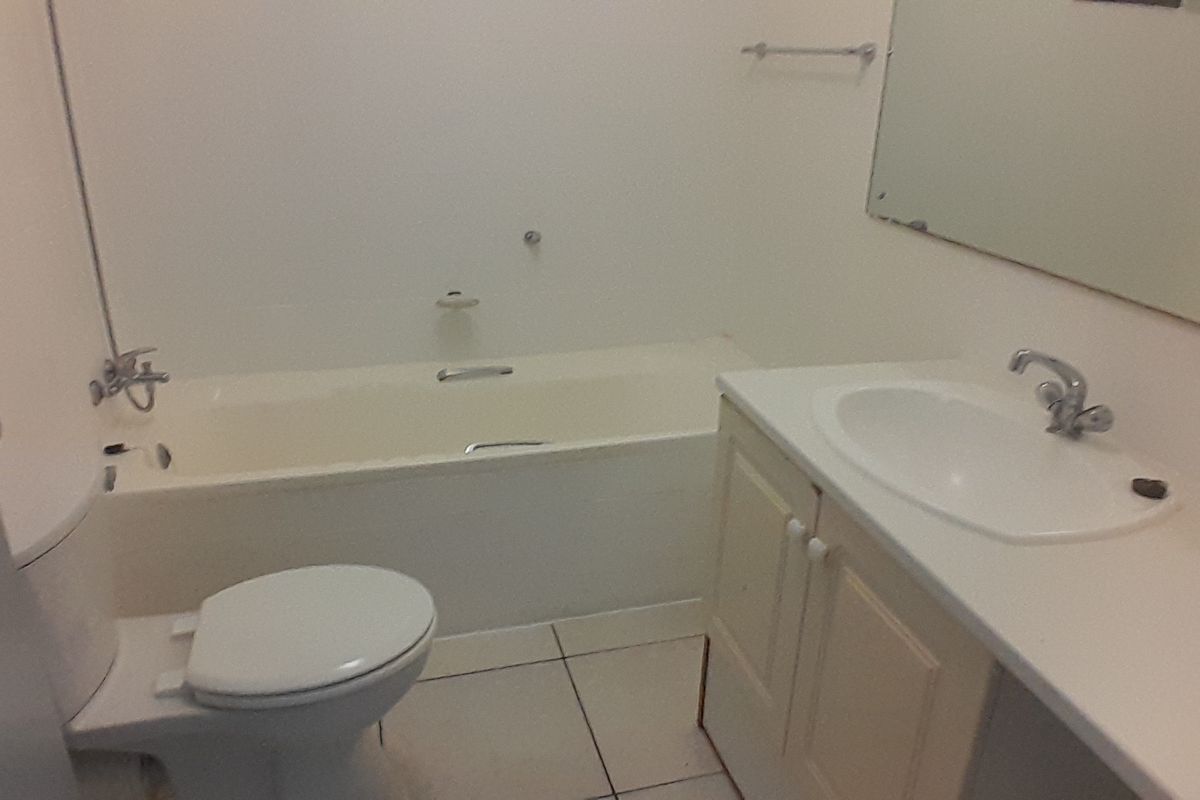 A functional bathroom featuring a built-in bathtub, a vanity with an integrated basin, and a wall-mounted mirror.