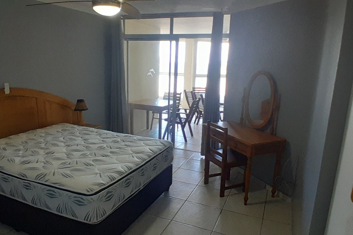 A bedroom featuring tiled flooring, a ceiling fan, and sliding glass doors that open onto an attached balcony.