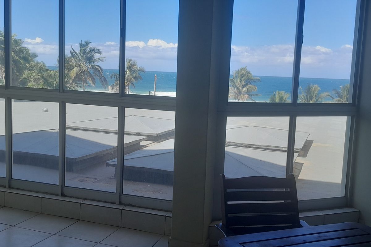 A bright living area featuring large floor-to-ceiling windows that offer expansive ocean views and natural light.