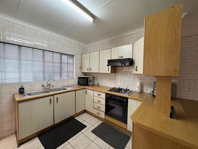 A functional kitchen featuring laminate cabinetry, a gas hob, built-in oven, extractor fan, and tiled backsplash with a double basin sink.