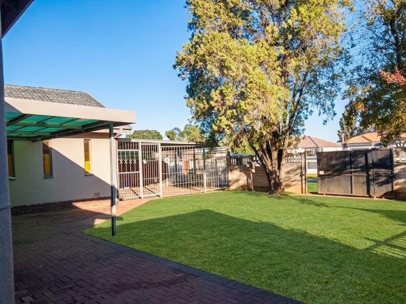 A well-maintained rear garden featuring a paved patio area with a pergola, secure fencing, and a neat lawn.