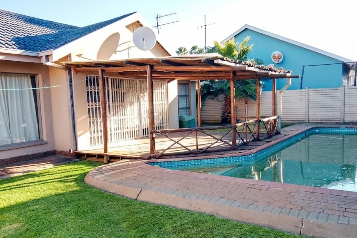 Outdoor pool area featuring a timber deck with a pergola, brick paving, and a swimming pool, providing a functional space for outdoor relaxation.