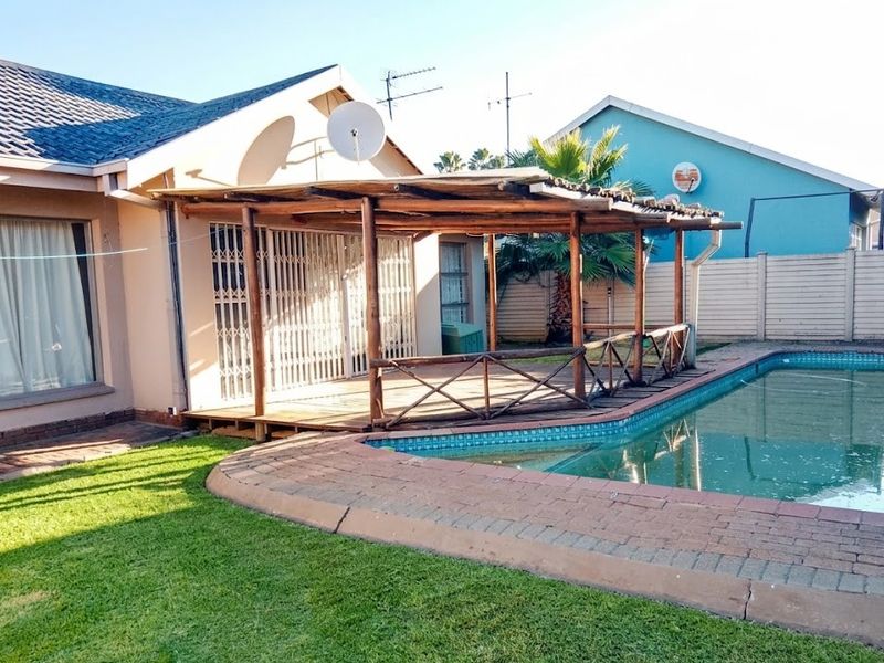 Outdoor pool area featuring a timber deck with a pergola, brick paving, and a swimming pool, providing a functional space for outdoor relaxation.