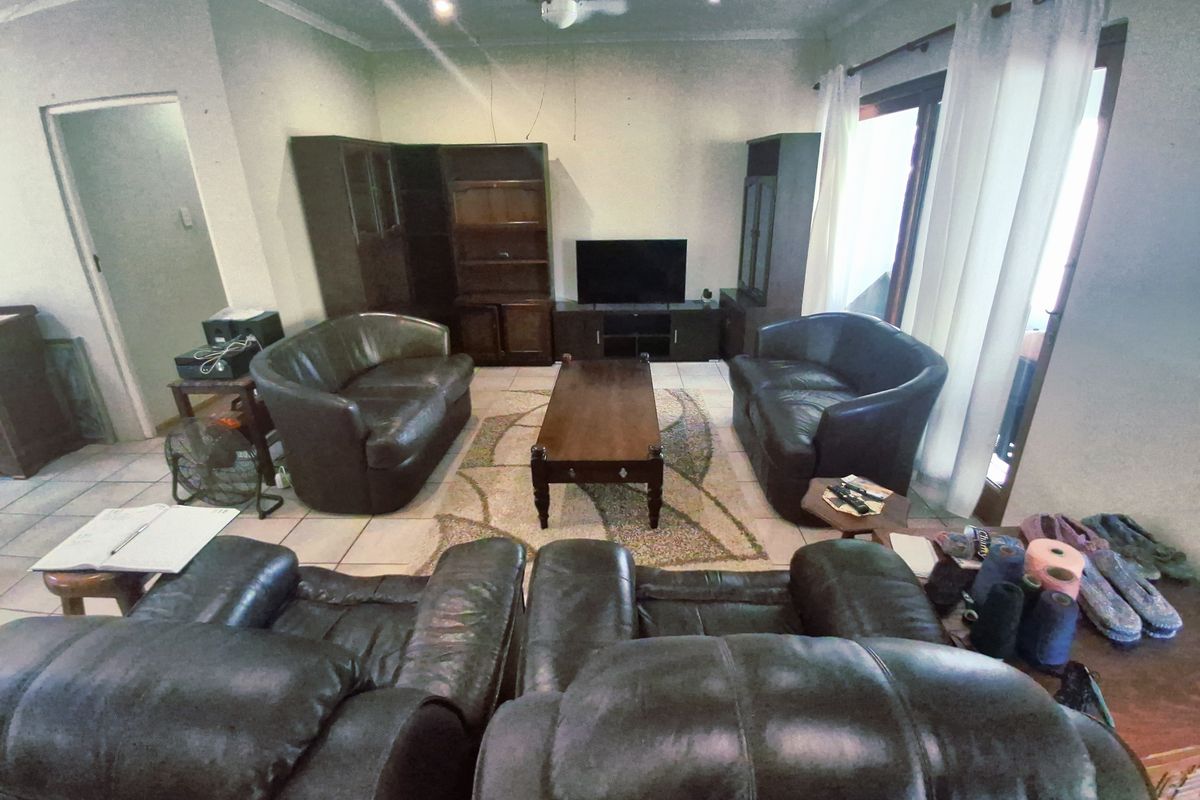 A spacious living room featuring tiled flooring, a ceiling fan, and large sliding glass doors providing access to the exterior.