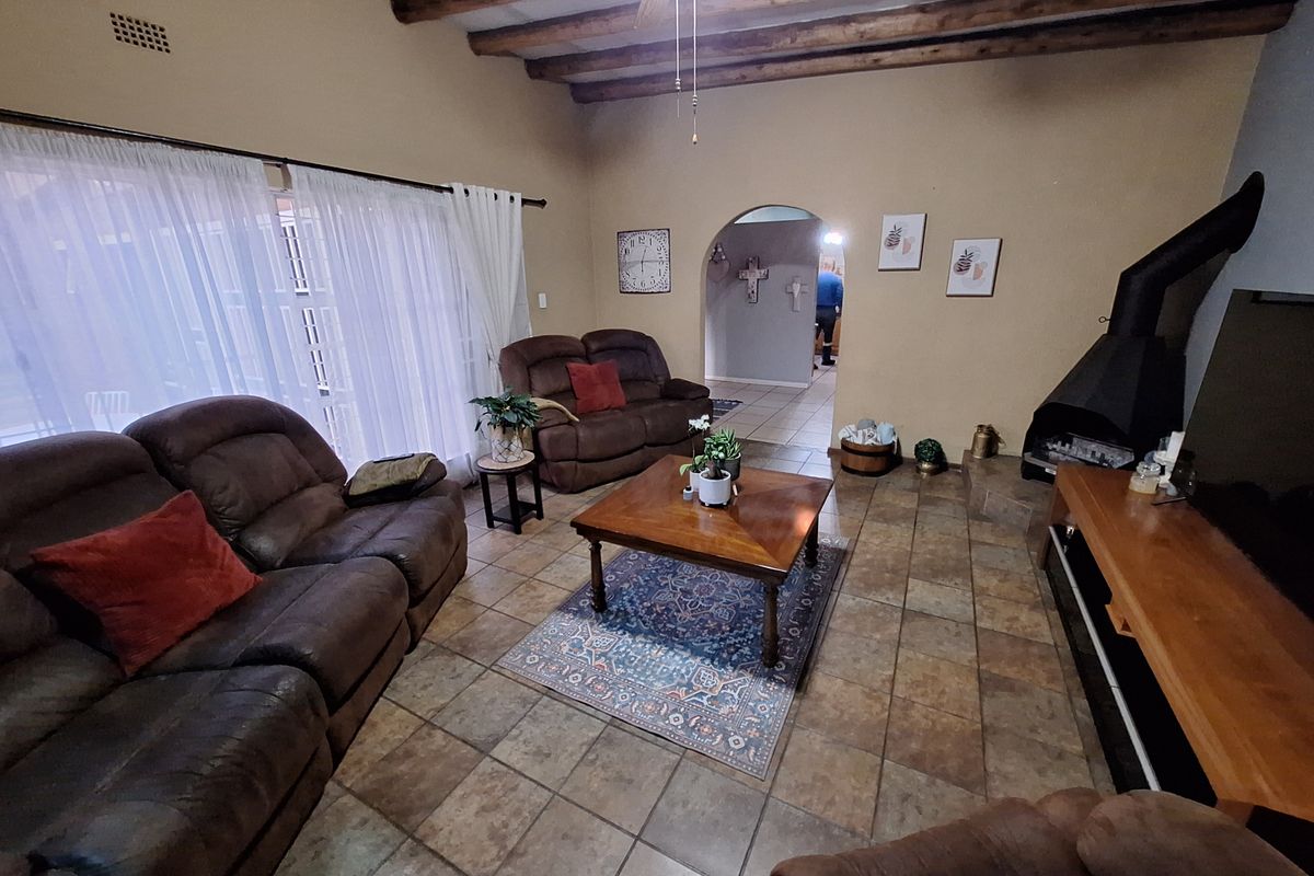Spacious living room featuring exposed timber ceiling beams, tiled flooring, and a prominent freestanding fireplace, creating a warm and inviting atmosphere.