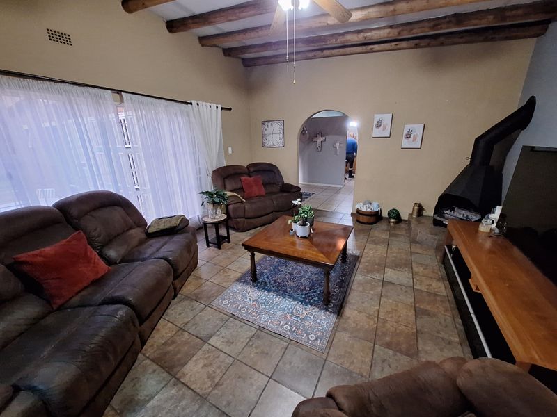 Spacious living room featuring exposed timber ceiling beams, tiled flooring, and a prominent freestanding fireplace, creating a warm and inviting atmosphere.
