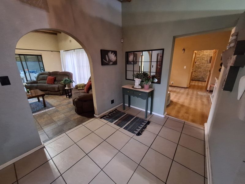 Welcoming entrance hall featuring an arched doorway leading to the living area, with neutral tiled flooring and access to adjacent rooms.