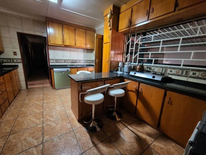 A functional kitchen featuring wooden cabinetry, granite countertops, a built-in stove, and tiled flooring, offering a traditional layout with ample storage space.