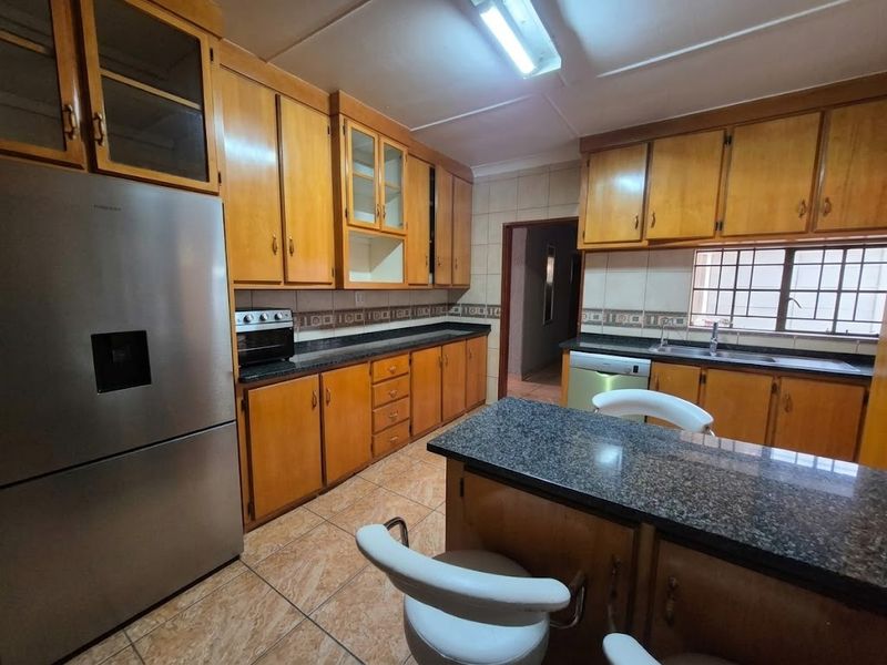 A functional kitchen featuring wooden cabinetry, granite countertops, tiled flooring, and a built-in oven, offering a classic layout with ample storage space.