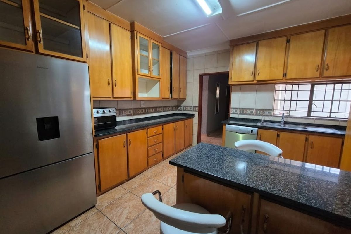 A functional kitchen featuring wooden cabinetry, granite countertops, tiled flooring, and a built-in oven, offering a classic layout with ample storage space.