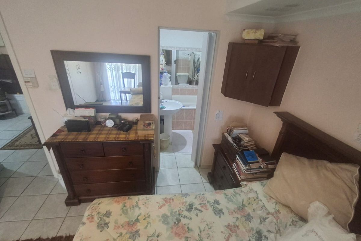 A bedroom featuring tiled flooring and direct access to an en-suite bathroom equipped with a pedestal basin and bathtub.