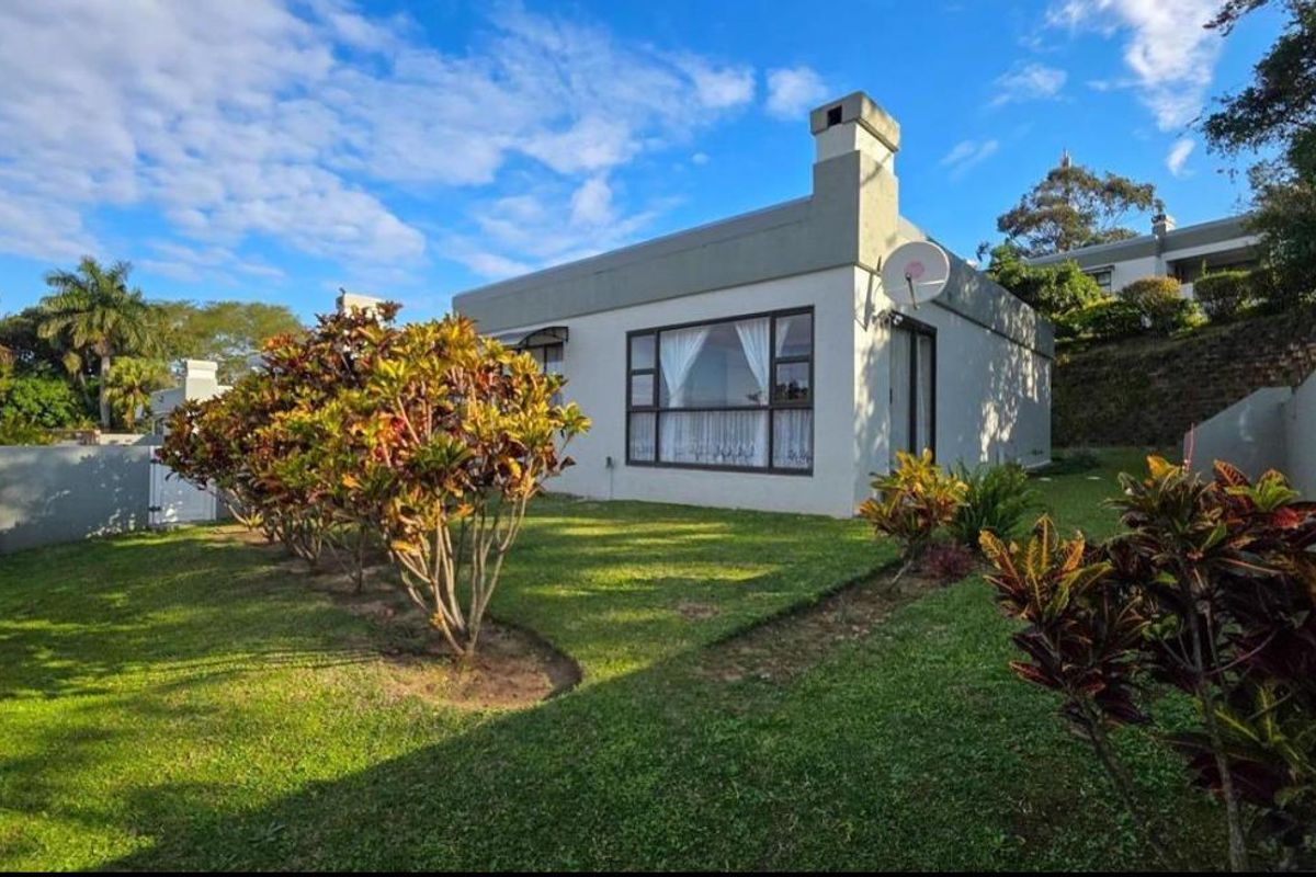 Rear view of the townhouse featuring a private garden, lawn, chimney, and large windows providing natural light.