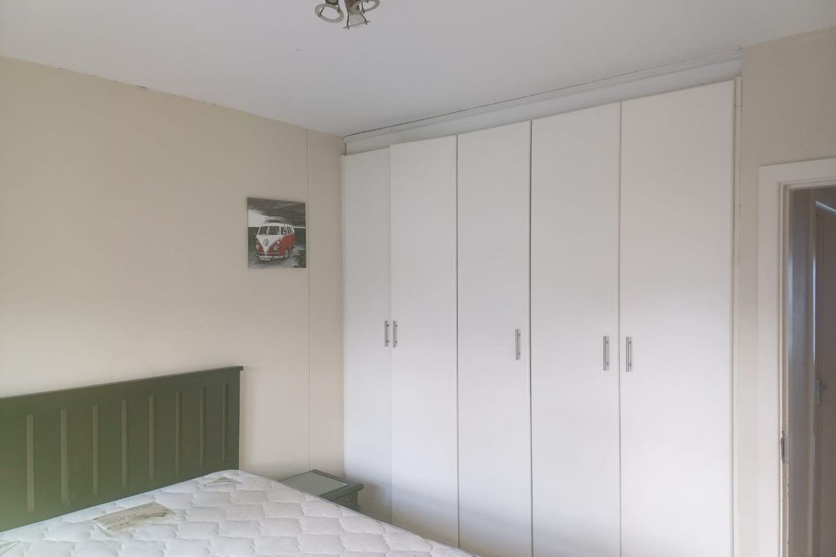 A bedroom featuring built-in white wardrobes with silver handles, providing ample storage space.