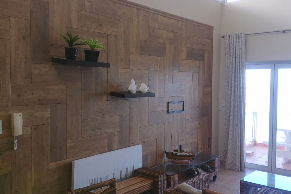 Living room featuring a decorative herringbone wood-paneled feature wall and large sliding glass doors providing access to an outdoor balcony area.