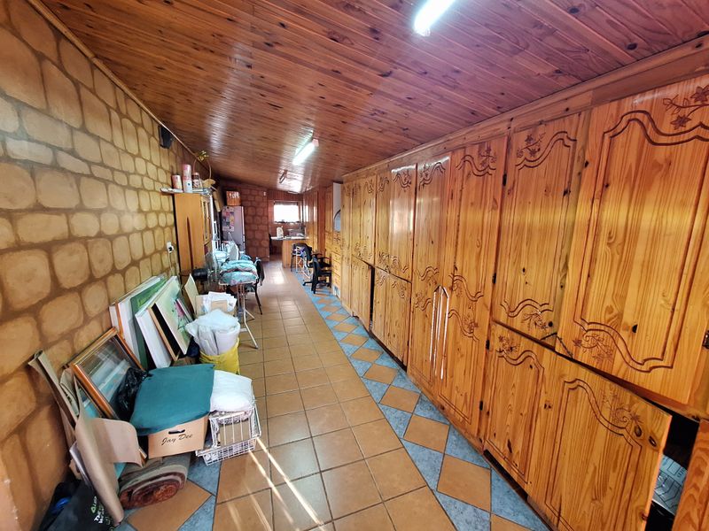 A long hallway featuring extensive built-in wooden cabinetry, tiled flooring, and a timber-clad ceiling, offering significant storage potential.