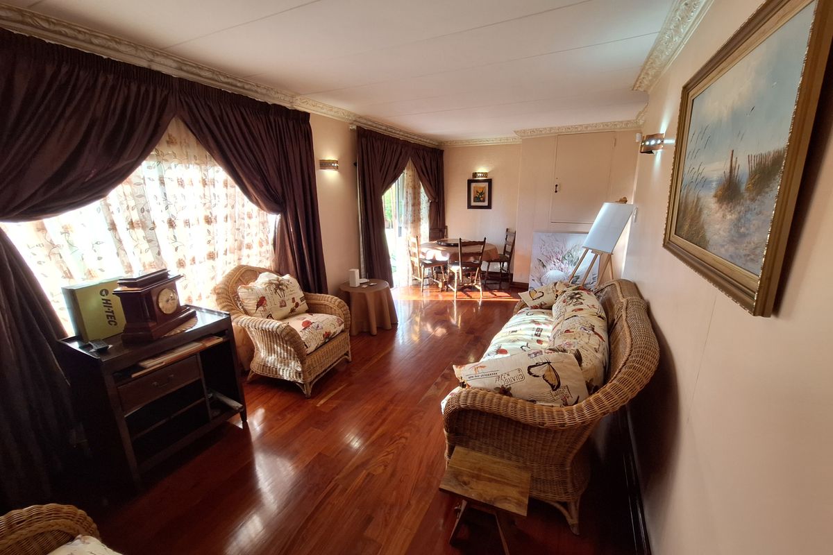 A spacious living room featuring polished hardwood flooring, decorative crown molding, and wall sconce lighting, offering a warm and inviting atmosphere.