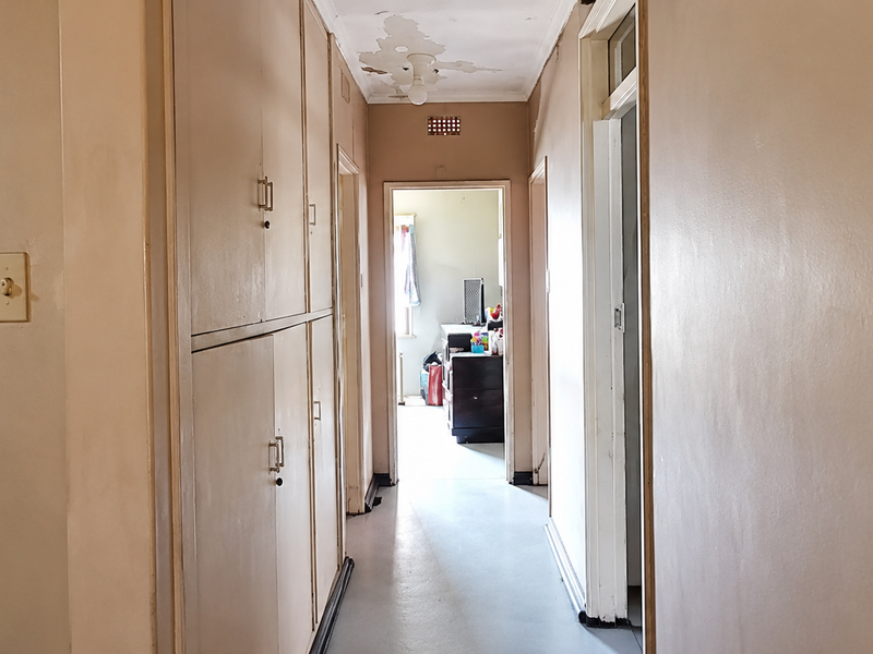 A hallway featuring built-in storage cabinetry, requiring ceiling repairs due to visible paint peeling and water damage.