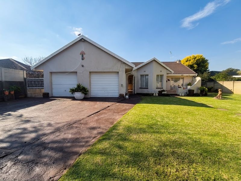 Front view of a residential house featuring a double garage, paved driveway, and a well-maintained front lawn.