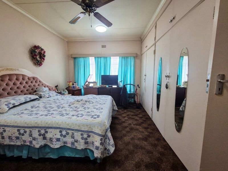 A bedroom featuring built-in cupboards, a ceiling fan, and carpeted flooring.