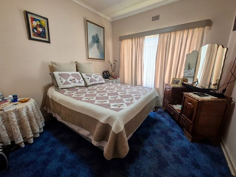 A bedroom featuring blue carpet flooring, a curtain rail, and a ventilation grille.