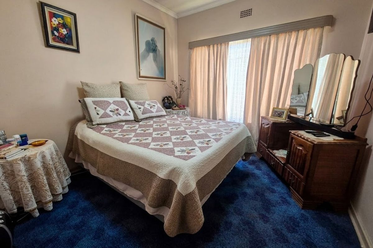 A bedroom featuring blue carpet flooring, a curtain rail, and a ventilation grille.
