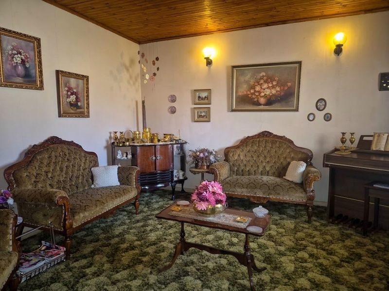 A traditional living room featuring a timber-paneled ceiling and wall-mounted lighting, currently finished with dated carpeting.
