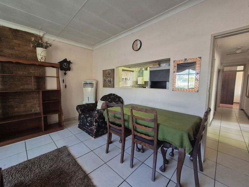 Dining area featuring tiled flooring, a brick feature wall, and a convenient serving hatch connecting to the kitchen.