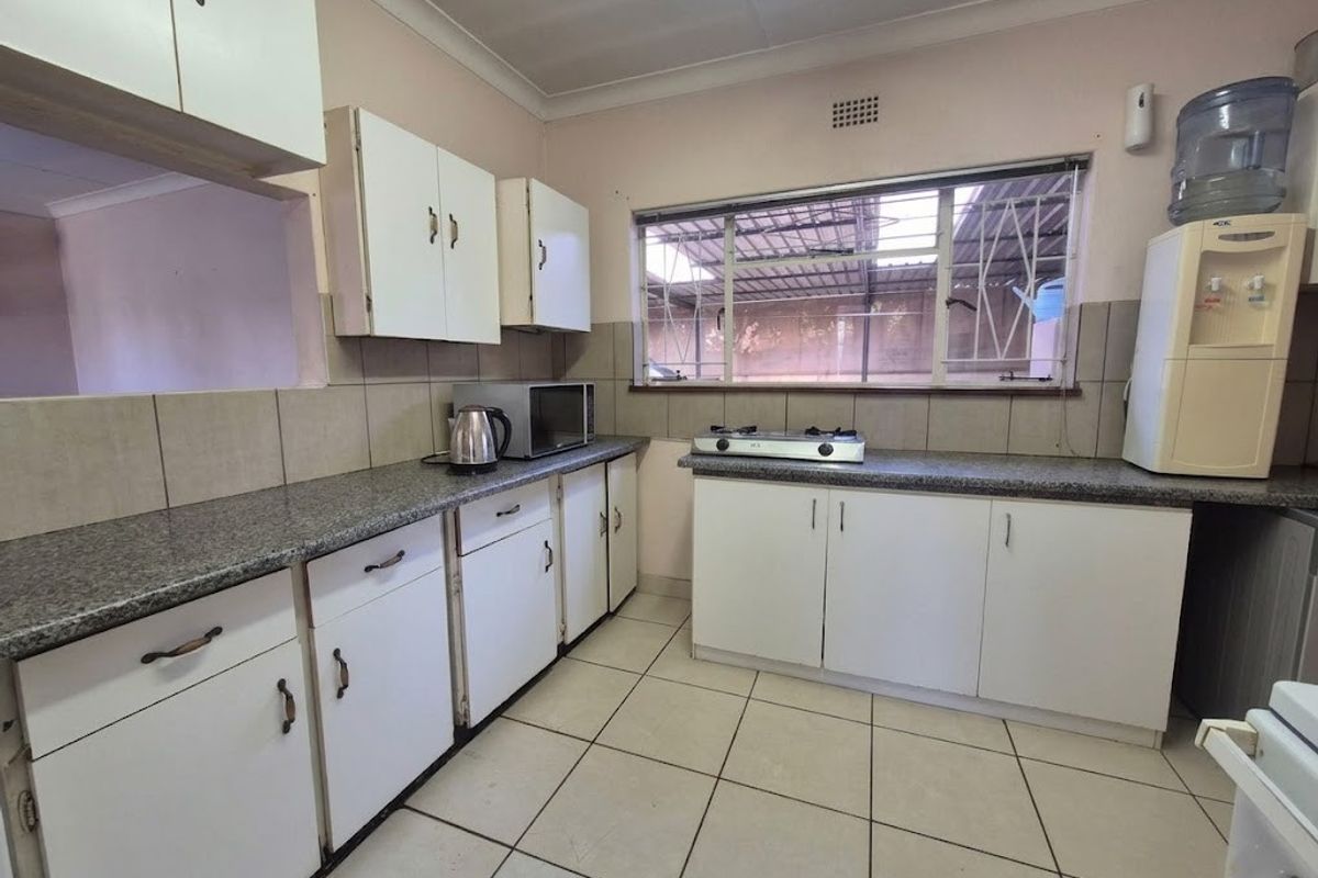 Functional kitchen featuring granite countertops, white cabinetry, tiled flooring, and a tiled backsplash with a window overlooking the exterior.
