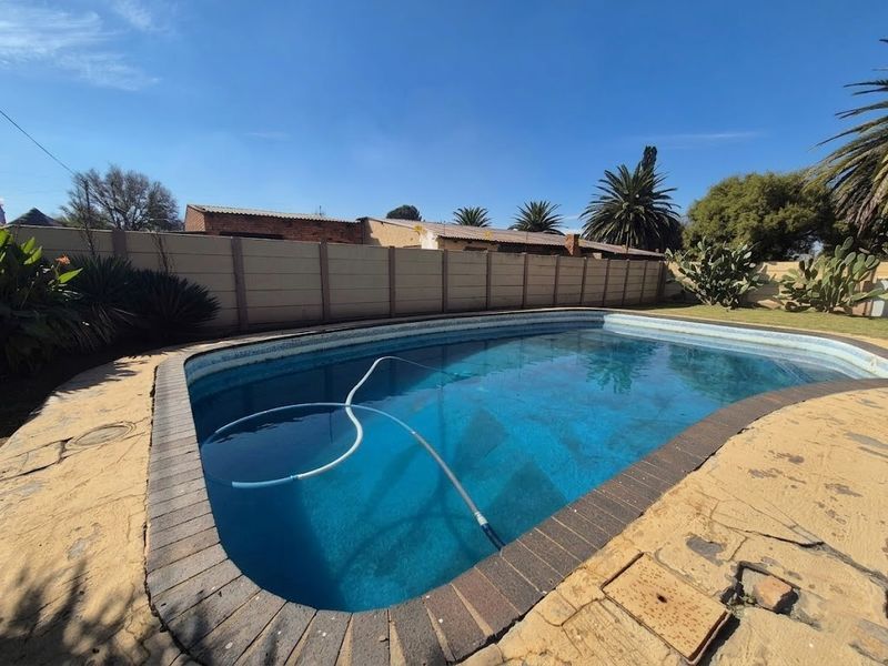 Outdoor swimming pool area featuring a paved surround and precast concrete boundary wall, providing a private space for recreation and relaxation.