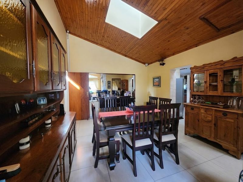 Spacious dining room featuring a vaulted timber ceiling with a skylight, tiled flooring, and built-in wooden cabinetry.