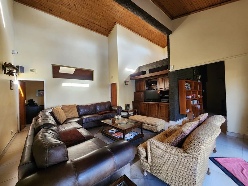 Spacious living room featuring a high vaulted timber ceiling, exposed brick accents, and custom built-in cabinetry, offering a warm and traditional aesthetic.