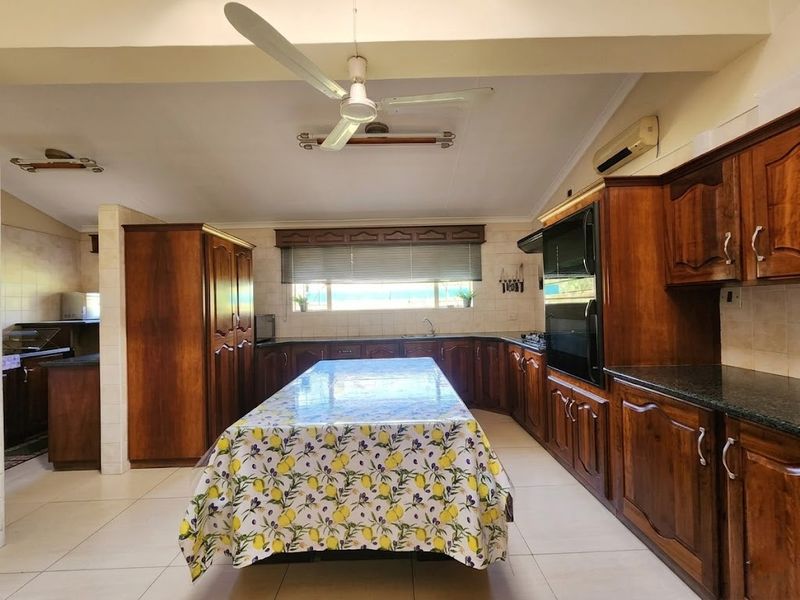 Spacious kitchen featuring extensive wooden cabinetry, built-in appliances, tiled flooring, and a central island, offering a functional layout with ample storage space.