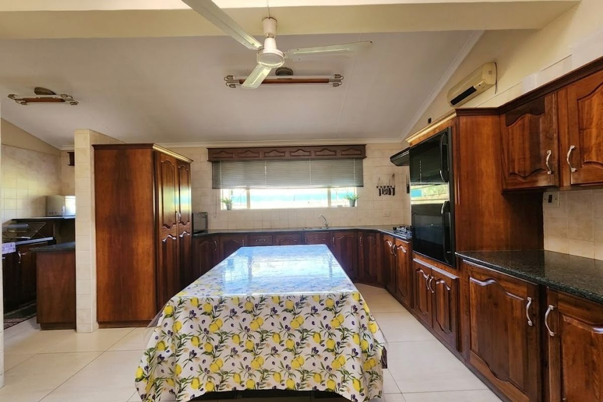 Spacious kitchen featuring extensive wooden cabinetry, built-in appliances, tiled flooring, and a central island, offering a functional layout with ample storage space.