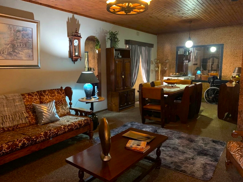 Open plan living and dining area featuring timber ceiling paneling and cork wall finishes, offering a traditional aesthetic with potential for modernization.