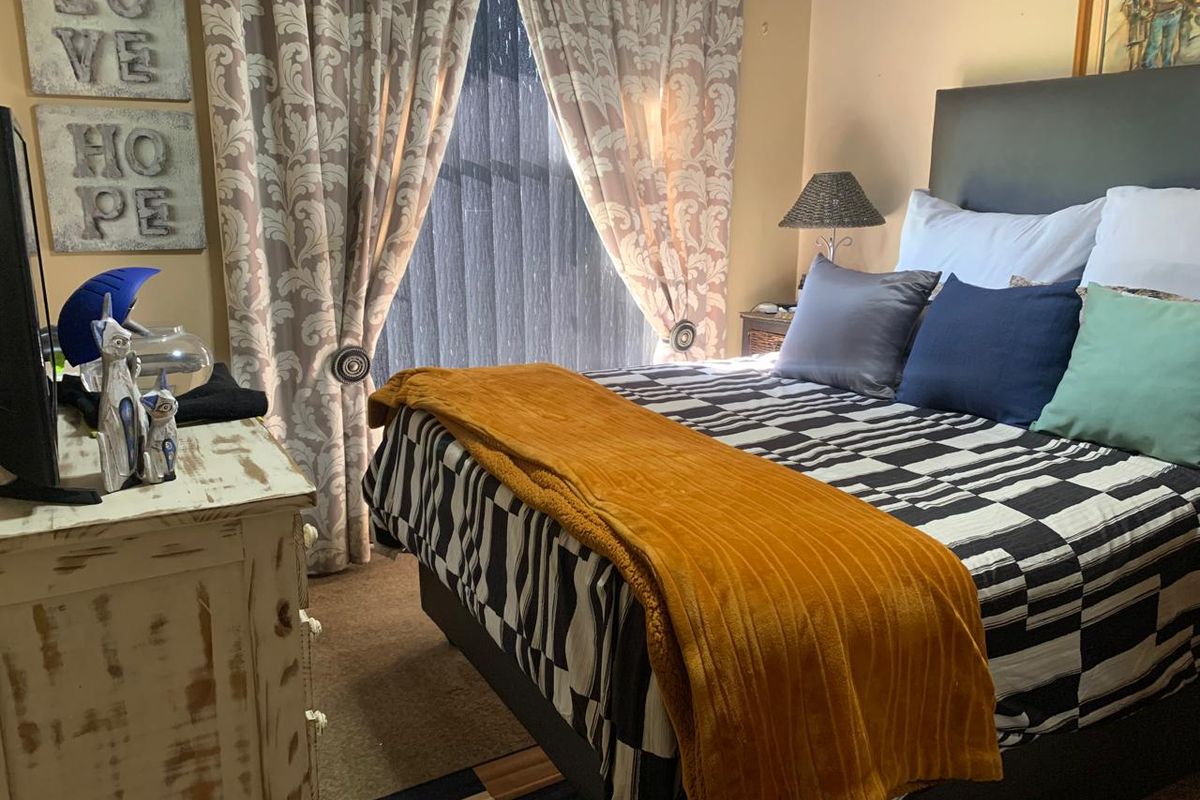 A cozy bedroom featuring a window with decorative curtains and neutral wall finishes.
