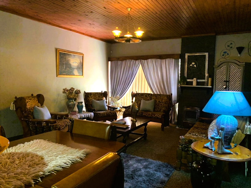 A traditional living room featuring a timber-clad ceiling, a brick fireplace with an integrated insert, and a large window with a timber pelmet.